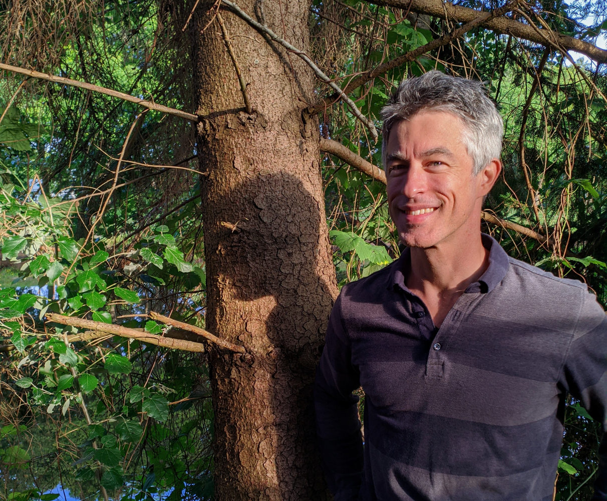 photo of Owen King smiling and standing in front of a tree
